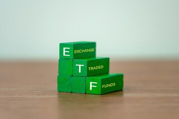Three wooden blocks spelling out "ETF" vertically, with the full words "EXCHANGE TRADED FUNDS". Investment, financial products, stock market trading concept.