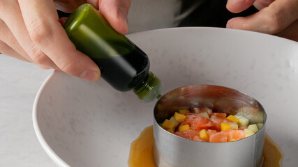 A pair of hands enliven a gourmet ceviche with emerald elixir, evoking Earth Day's vibrant renewal...