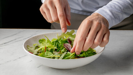 White male hands artfully arranging verdant salad, embodying mindful feasting, Earth Day celebrations, and seasonal equinox rituals