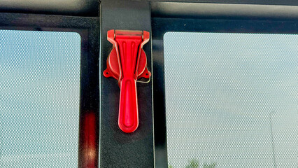 Vivid crimson emergency bus hammer on a window, an unsung hero of transportation safety, echoes...