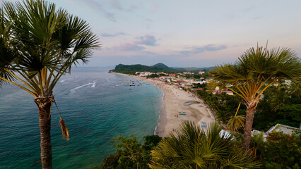 White Beach, Puerto Galera, Mindoro Island, Philippines. Tropical landscape. View of the sandy beach, promenade, cafes and restaurants on the shore, palm trees, jet skis and boats in the water.