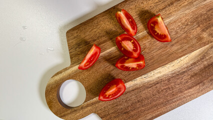 Vibrant tomato wedges cascade on rustic wooden board, evoking summer picnic nostalgia and...