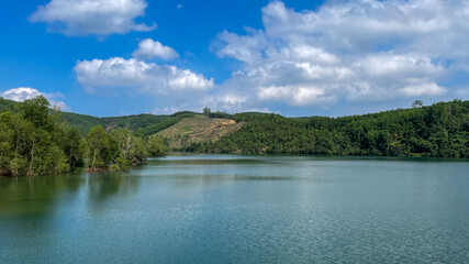 Serene emerald lake cradled by lush hills, invoking Earth Day reflection and Japanese Hanami springtime tranquility