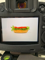 Food photography of burger. A vibrant hot dog nestled in a camera viewfinder teases retro picnic...