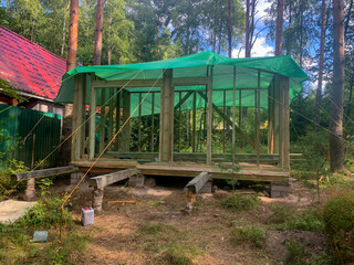 Rustic forest cabin skeleton under emerald tarp, whispers of eco-retreats, Ostara festivities, and woodland rejuvenation rituals call