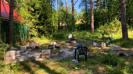 Sun-dappled clearing with empty chairs around a makeshift fire pit, echoing Midsummer folklore and secret garden gatherings