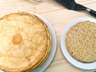 Golden crepes rest invitingly on white plates; a nod to Pancake Day's celebration and Maslenitsa's festive tapestry