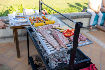 Chef grilling assorted meat and vegetables on barbecue for outdoor party