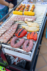 Grilling sausages, chicken legs, pork ribs, corn and peppers on barbecue grill