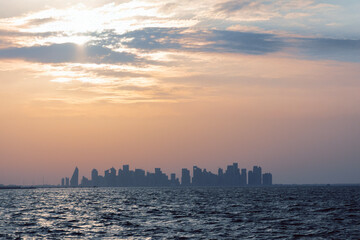 The sun sets perfectly over Doha skyline with warm orange sky. Qatar

