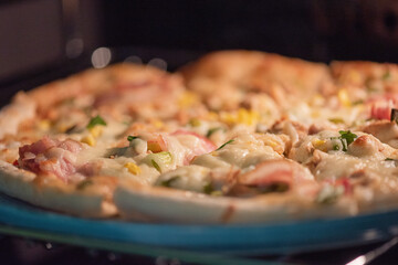 Ready-made pizza with bacon and cheese on a blue plate.