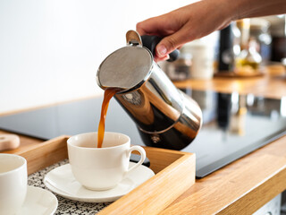 Pouring coffee from coffee pot into cups, close-up