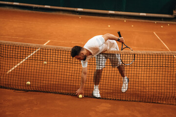 Front view. Man is playing tennis indoors in the hangar