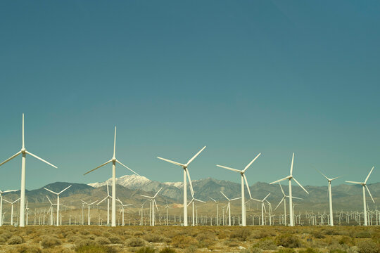 Wind turbines in a desert landscape with mountains in the background under a clear sky. Mojave Desert, USA