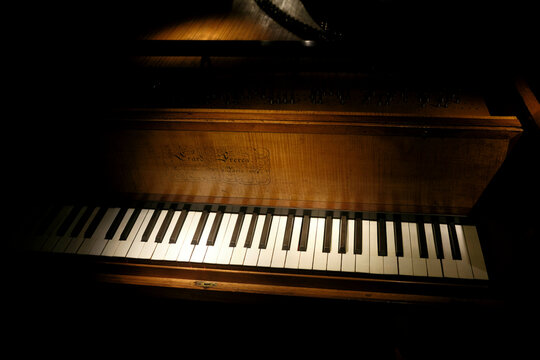 Close-up of a wooden piano keyboard in dim, dramatic lighting.