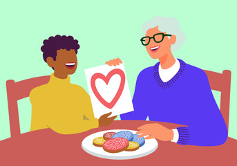 Grandson gifts a heart drawing to his smiling grandmother over cookies. A sweet display of love and family connection. 