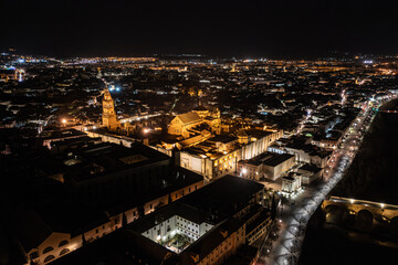 An aerial view showcases the stunning Mosque-Cathedral of Cordoba, with its distinctive bell tower and surrounding courtyards, bathed at night