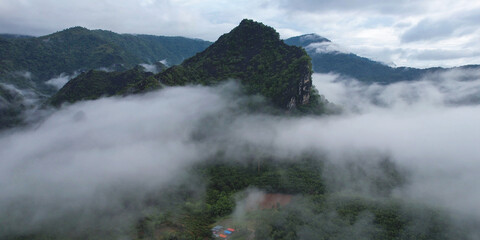 Aerial view of greenery mountains and rural village on foggy morning