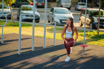 Athletic woman engaging in a workout at an outdoor fitness park. She is focused on her exercise...