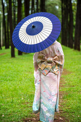 Vertical rear view unknown Japanese woman dressing in traditional kimono or yukata holding umbrella...