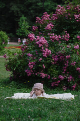 Child Lying on Blanket Surrounded by Pink Flowers