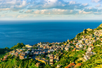 scenic view at beautiful mountain town on a sea coast in Italy with green hills, antique buildings and amazing blue sea on backgeound of landscape