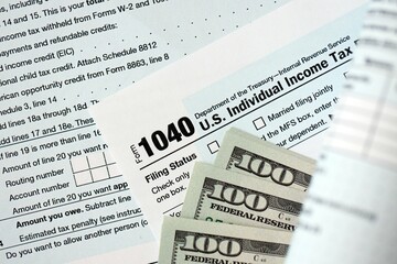 Hundred dollar bills and 1040 individual income tax return form blank close up