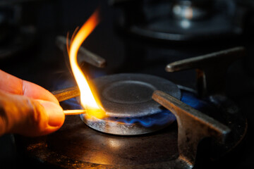 A hand lighting a gas stove burner with a match