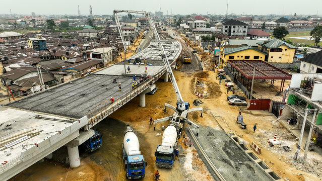 Aerial view of a modern flyover under construction with heavy machinery contrasting against the residential buildings, Port Harcourt, Rivers, Nigeria.