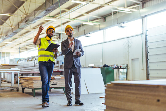 Two Professionals Discussing Plans in a Newly Constructed Industrial Workshop Space