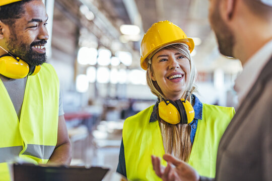 Group of Factory Workers Collaborating and Smiling in a Safe Work Environment