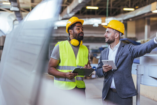 Two Workers Collaborating in an Industrial Facility While Discussing Details - Powered by Adobe