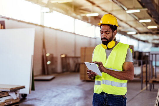 Construction Worker Using Tablet Device Inside Industrial Warehouse Facility