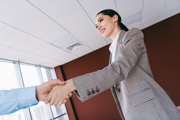 Confident businesswoman shaking hands in a modern office representing professional agreement and...