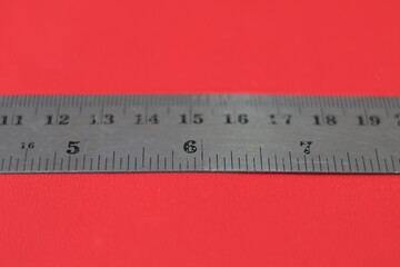 Iron ruler on a red background. Stainless steel ruler. a metal ruler with a scale on a red...