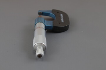 A blue screw micrometer isolated on grey background, A micrometer is a tool to precisely measure...