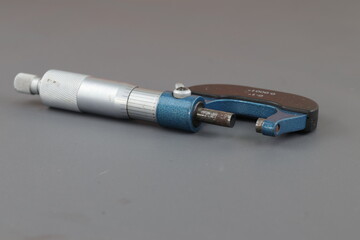 A blue screw micrometer isolated on grey background, A micrometer is a tool to precisely measure...