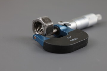 Metal nut tightened in micrometers isolated on grey background