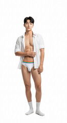 Fototapeta premium A fit young Asian male model poses confidently against a white backdrop. He wears a white open shirt, white underwear, and socks, highlighting his toned physique in a clean, stylish fashion look 