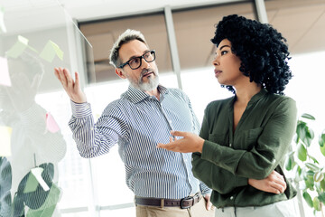 Two business professionals engaged in a collaborative planning session at a modern office workspace...
