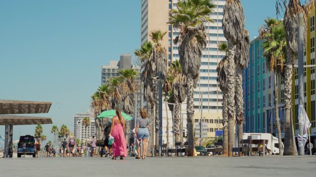 Tourists and locals walking on boardwalk or promenade in Tel Aviv beach. People strolling and sightseeing or going to swim in Mediterranean Sea in Israel during hot summer vacation outdoors