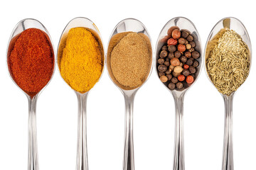 Assortment of vibrant spices on shiny spoons  isolated on white background