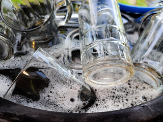 a stack of glasses in a bucket of soapy water