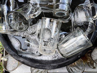 a stack of glasses in a bucket of soapy water