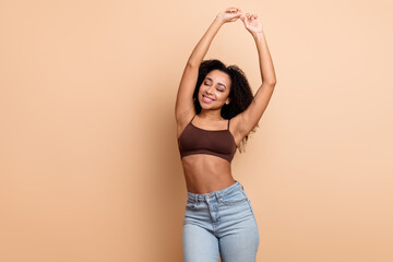 Young contemporary woman posing confidently in casual summer fashion against a beige background,...