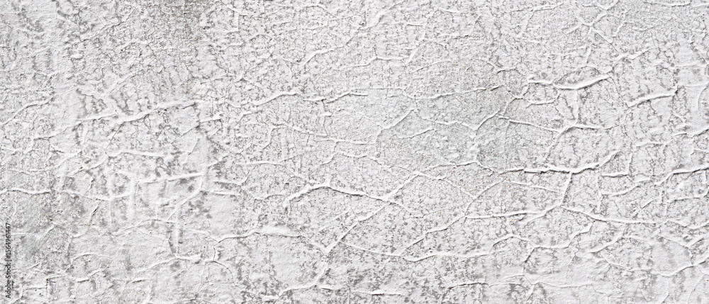 Poster wall is made of concrete and has white paint on it. cracks in paint, which givewall a rough texture.
