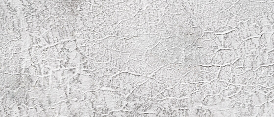 wall is made of concrete and has white paint on it. cracks in paint, which givewall a rough...