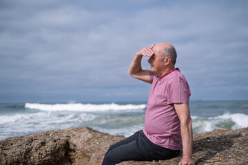 Elderly Man Sitting on the Beach and Looking at the Ocean, Remembering His Youth in Portugal
