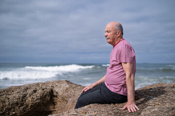 Elderly Man Sitting on the Beach and Looking at the Ocean, Remembering His Youth in Portugal