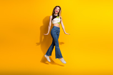 Excited Young Woman Jumping Joyfully Against a Bright Yellow Background, Embracing a Vibrant and Energetic Lifestyle
